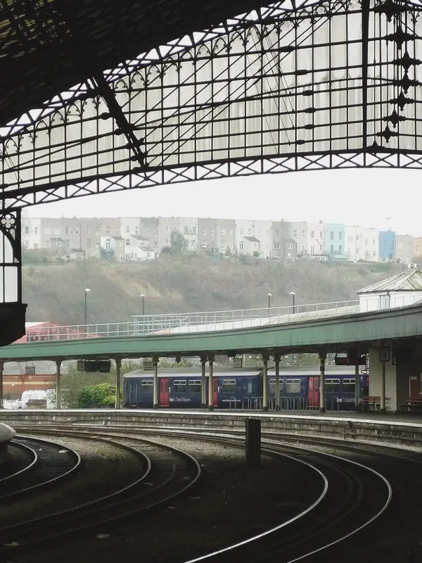 Curved tracks run under the trainshed's iron and glass end screen towards platforms in daylight.