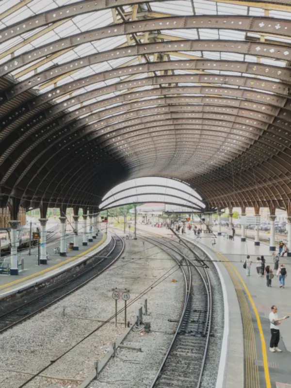 Curved iron roof spans sweep over platforms and tracks that bend towards a bright arched end.